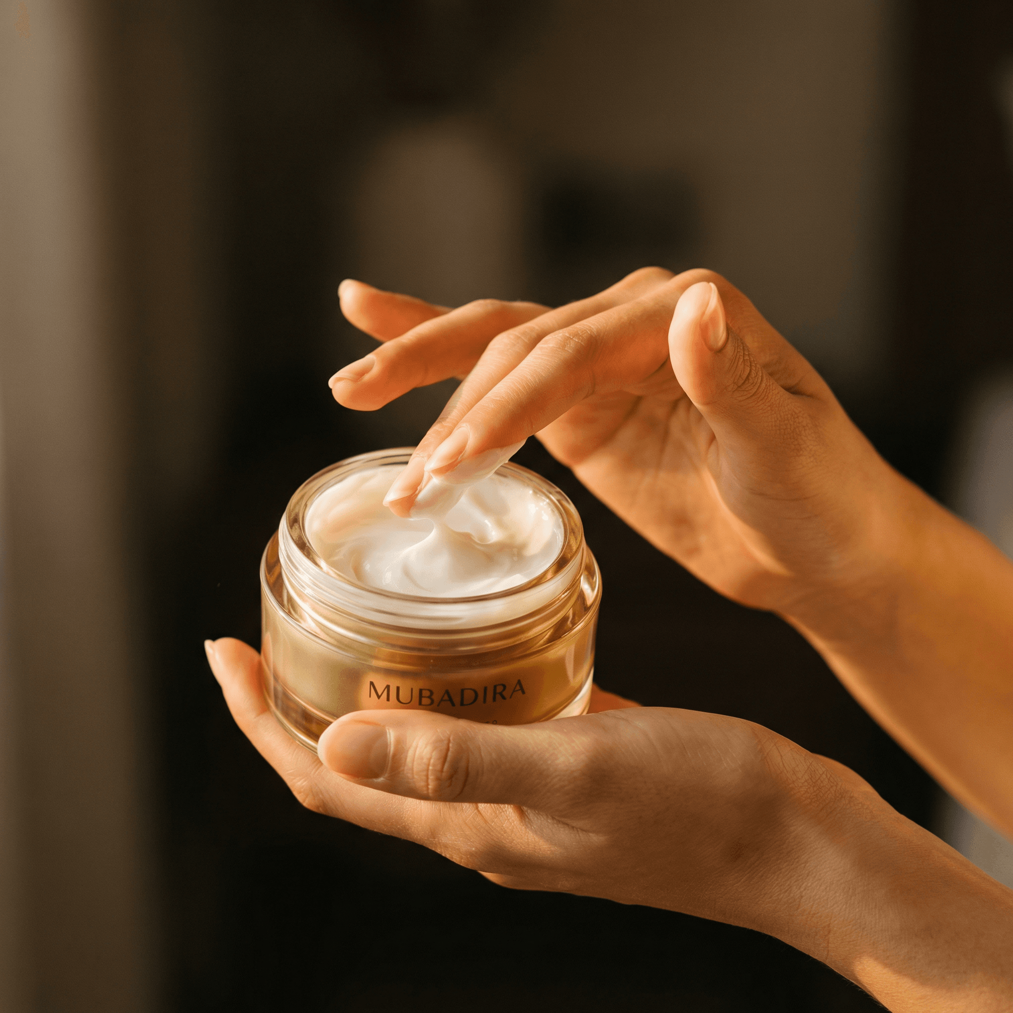 Elegant hands gently applying Mubadira cream